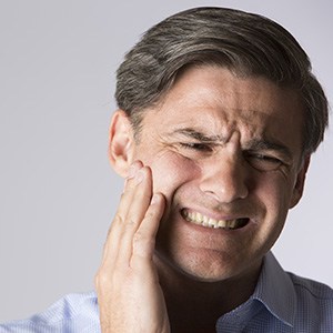 Older male patient grimacing and holding cheek
