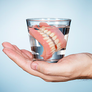 Full set of dentures in glass of water